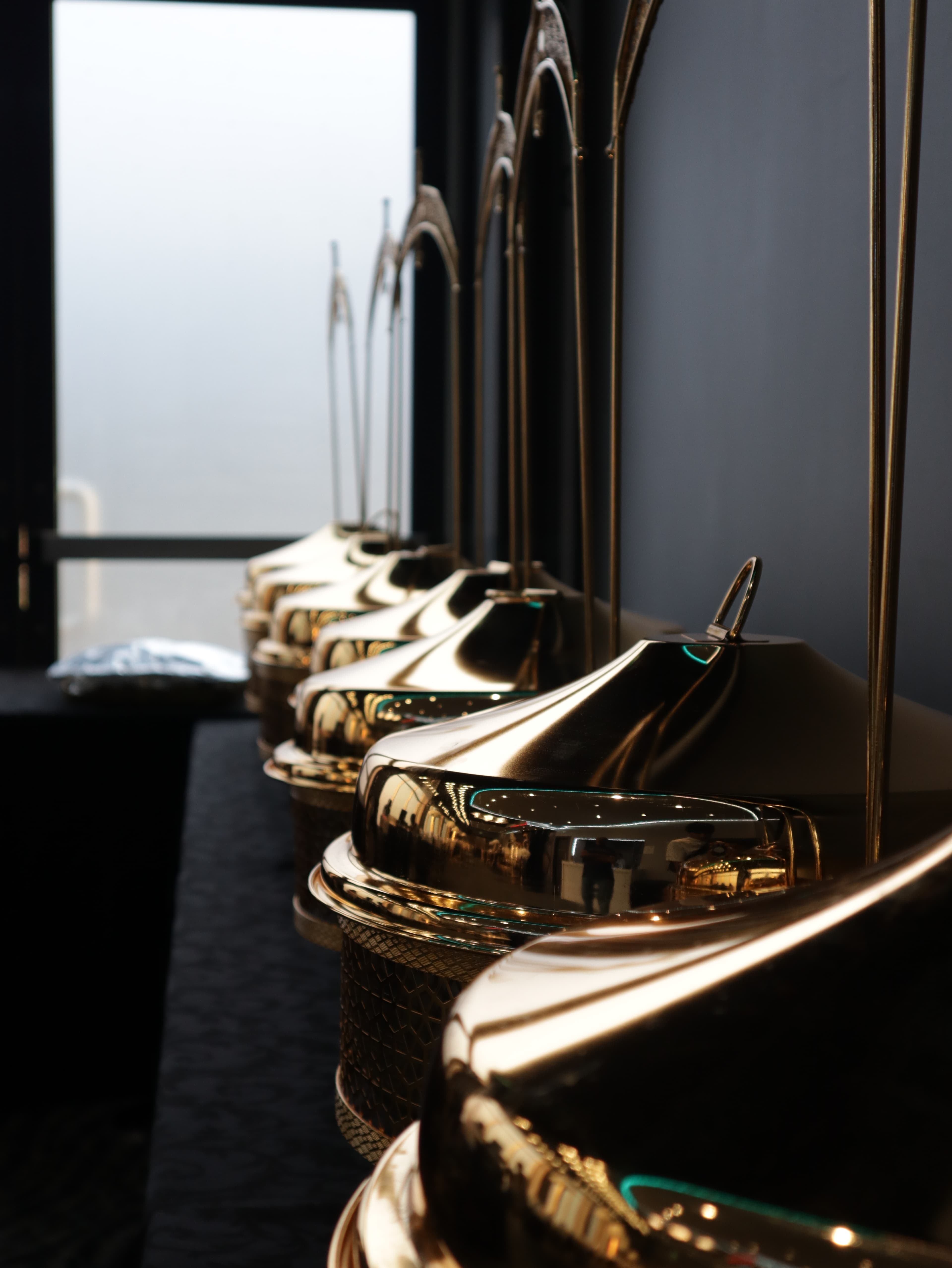 Row of gold catering chafing dish covers by a window